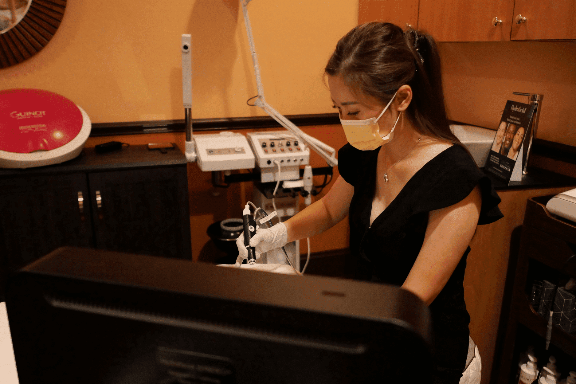 Woman in a clinic wearing a mask and gloves, preparing medical equipment for a procedure.